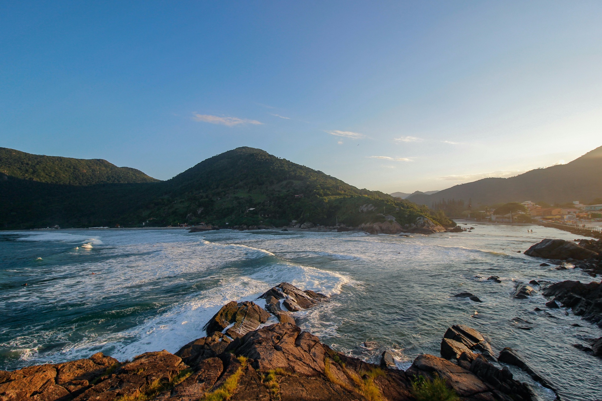 Pôr do sol na costa rochosa de Florianópolis com ondas chegando à enseada