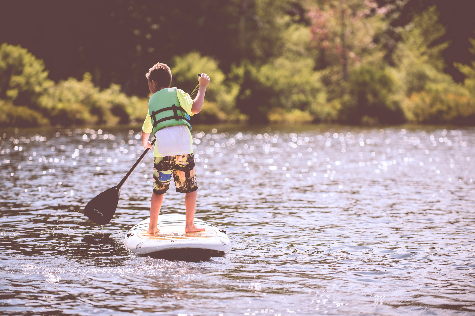 Young paddleboarder gliding across sparkling water